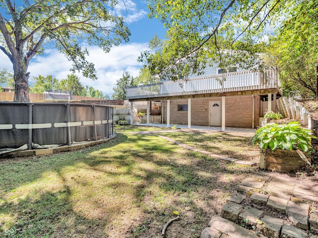 view of yard with a wooden deck, fence, a pool, and a patio