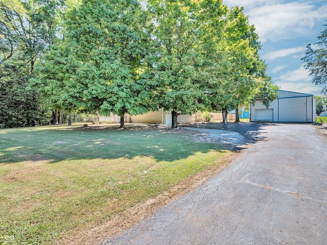 view of front of property featuring a garage, a front yard, an outdoor structure, and driveway