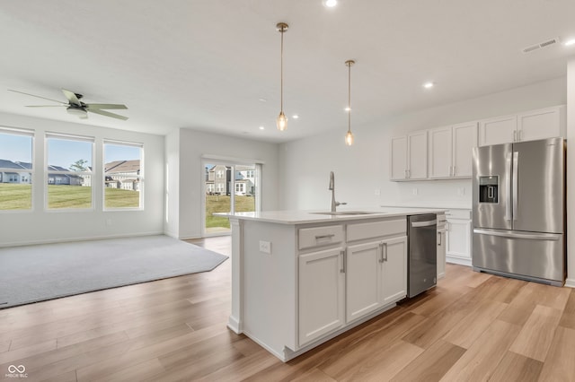 kitchen featuring a kitchen island with sink, white cabinets, stainless steel appliances, and sink