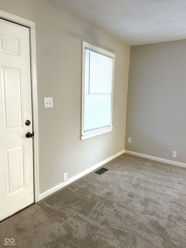 unfurnished room with carpet and a textured ceiling