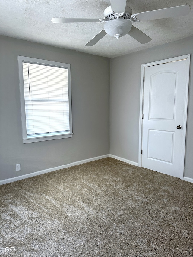 unfurnished room featuring ceiling fan, carpet floors, and a textured ceiling