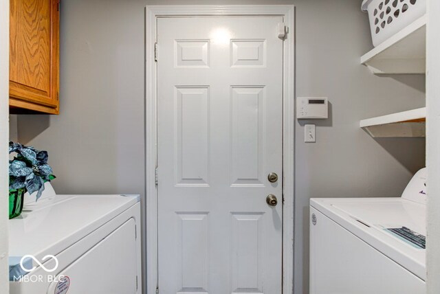 clothes washing area with cabinets and separate washer and dryer