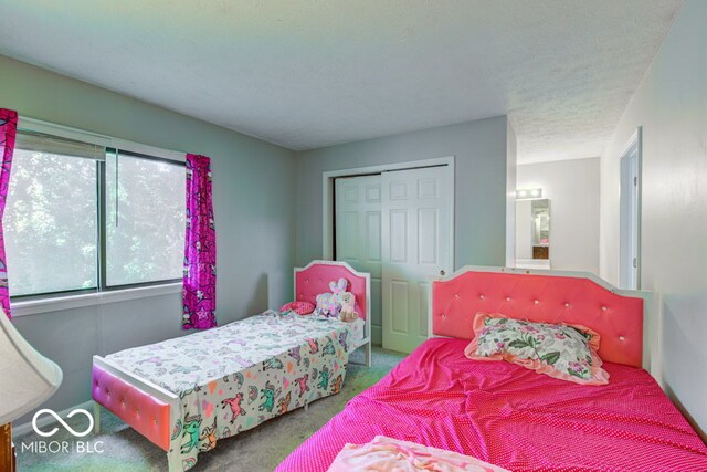 bedroom with a textured ceiling, a closet, and carpet flooring