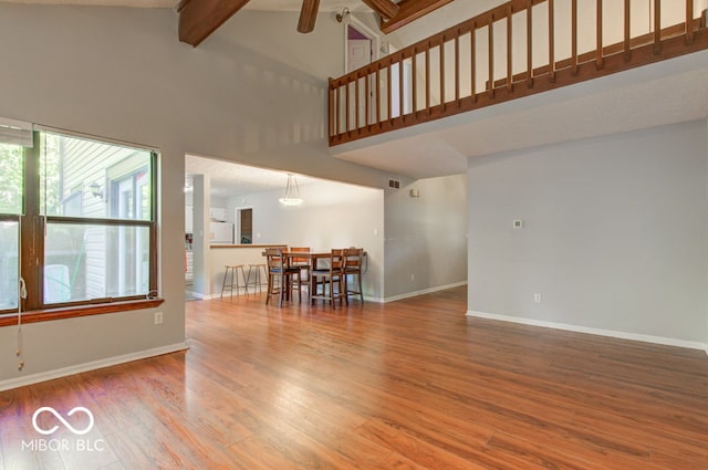 living room with wood finished floors, baseboards, high vaulted ceiling, ceiling fan, and beamed ceiling