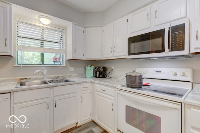 kitchen with white appliances, white cabinets, light countertops, and a sink