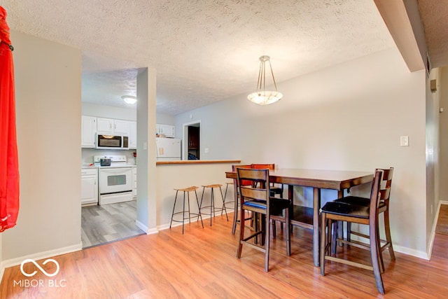 dining room with a textured ceiling and light hardwood / wood-style flooring