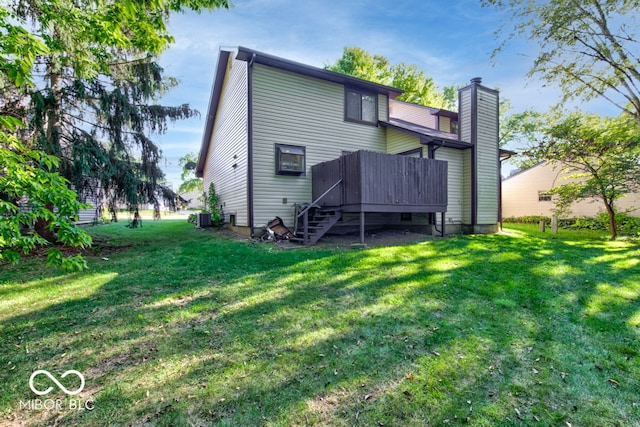 rear view of house with a deck, stairs, a lawn, and a chimney