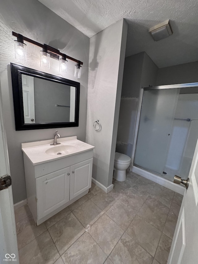 full bathroom featuring a shower stall, baseboards, toilet, vanity, and a textured ceiling