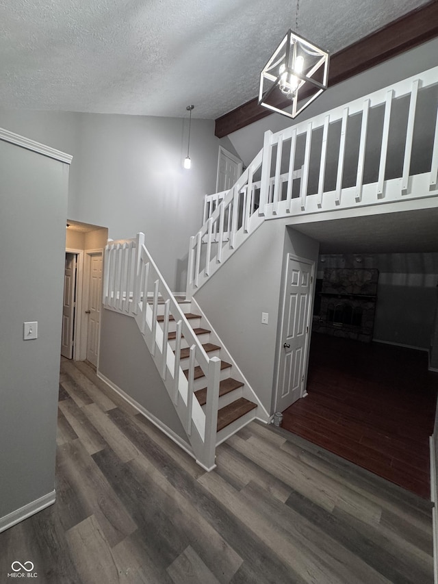 stairway featuring hardwood / wood-style floors, a textured ceiling, and vaulted ceiling with beams