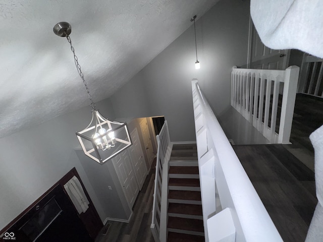 stairs featuring a textured ceiling, a chandelier, and vaulted ceiling