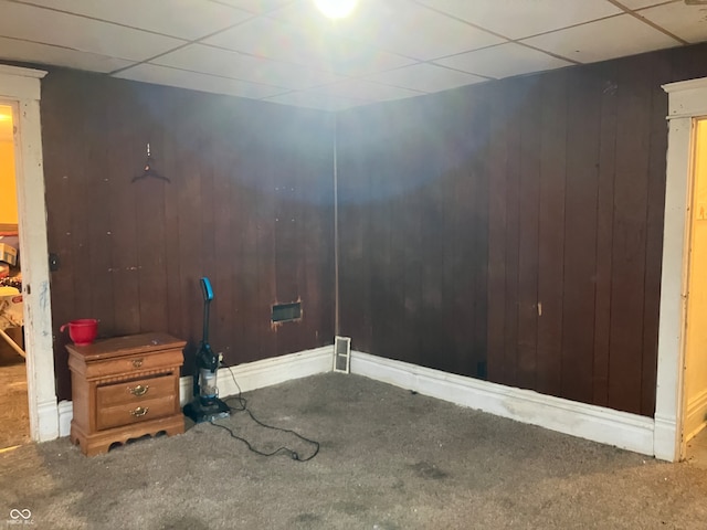 empty room with a paneled ceiling and wooden walls