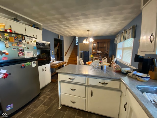 kitchen with stainless steel refrigerator, a notable chandelier, white cabinetry, oven, and hanging light fixtures