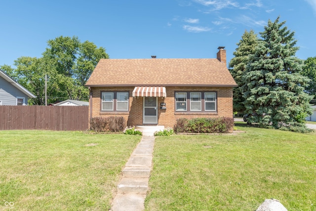 view of front of house with a front lawn, fence, brick siding, and a chimney