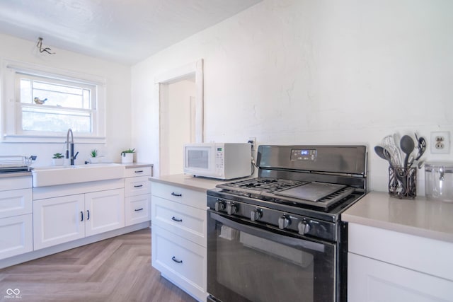 532 E Mills Ave, Indianapolis, IN 46227 - kitchen featuring white microwave, black range with gas stovetop, light countertops, white cabinets, and a sink