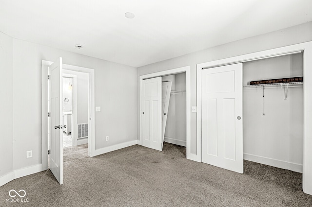 unfurnished bedroom featuring carpet and two closets