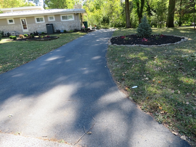 view of property exterior featuring a yard, stone siding, a chimney, and central AC