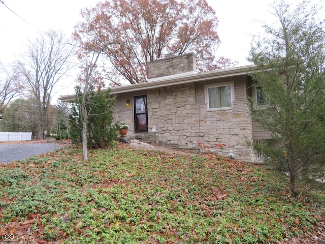 single story home with fence, stone siding, and a chimney