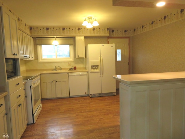 kitchen featuring pendant lighting, light hardwood / wood-style floors, white appliances, and sink