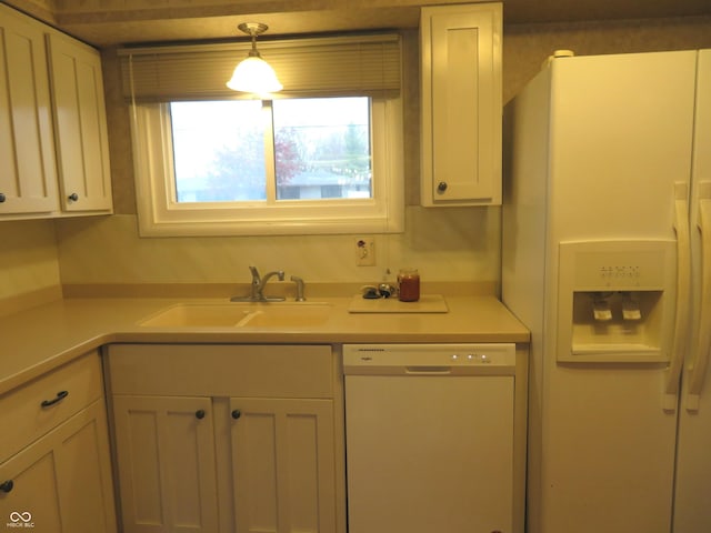 kitchen featuring white appliances, sink, and hanging light fixtures