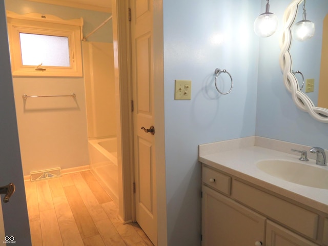 bathroom featuring vanity, wood finished floors, visible vents, and tub / shower combination