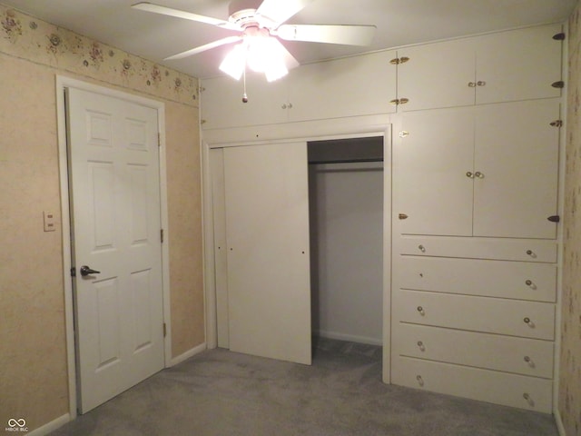 unfurnished bedroom with ceiling fan and dark colored carpet