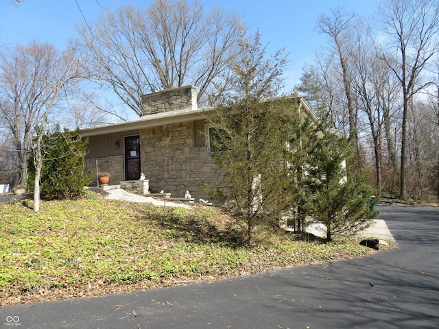 view of front facade with stone siding and a chimney