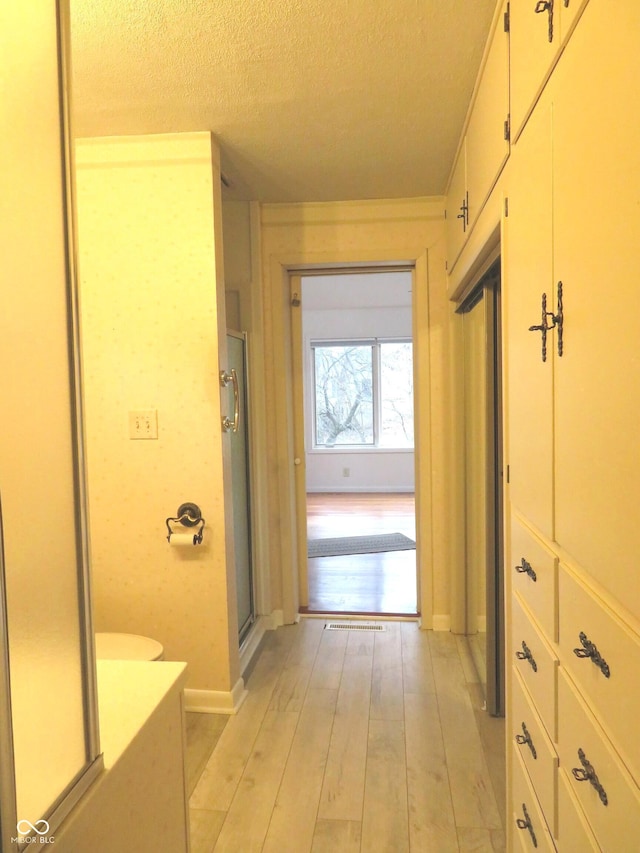 bathroom featuring a shower stall, a textured ceiling, and wood finished floors