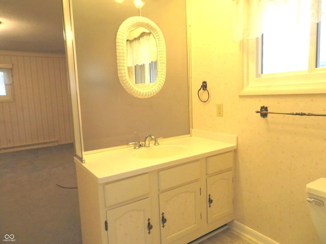 bathroom with a healthy amount of sunlight, toilet, vanity, and baseboards