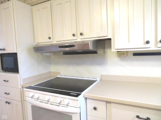 kitchen with electric stove, under cabinet range hood, white cabinetry, black microwave, and light countertops