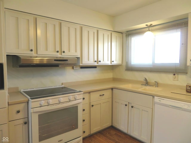 kitchen featuring a sink, under cabinet range hood, light countertops, white appliances, and dark wood-style flooring