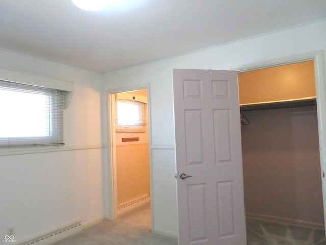 unfurnished bedroom featuring a baseboard radiator, light carpet, baseboards, and a closet