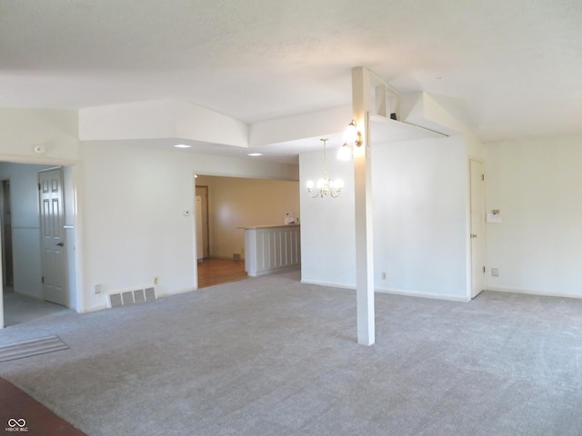 unfurnished living room with visible vents, baseboards, light colored carpet, and an inviting chandelier