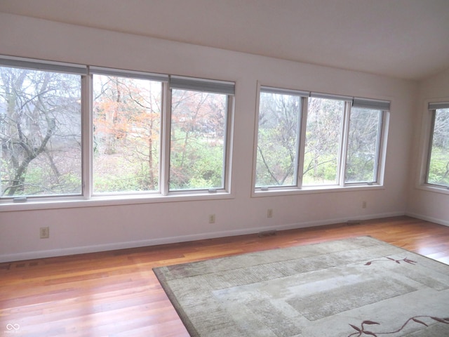 unfurnished room with light wood finished floors, visible vents, and baseboards