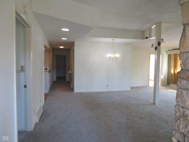 unfurnished room featuring a barn door, carpet, visible vents, and an inviting chandelier