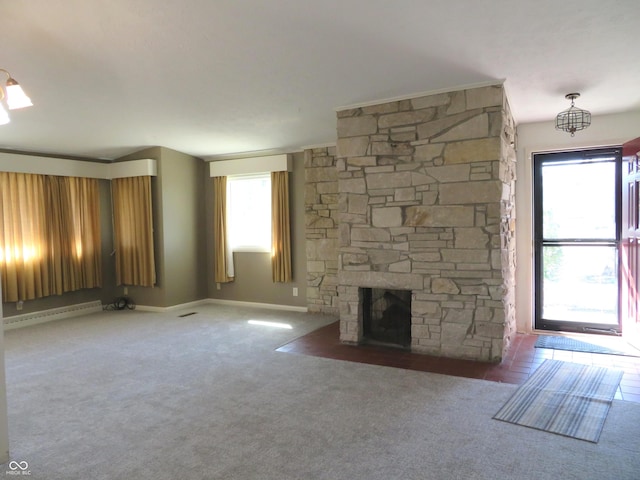 unfurnished living room featuring a baseboard heating unit, plenty of natural light, a stone fireplace, and carpet flooring