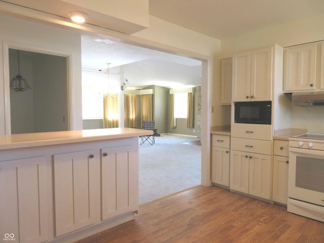 kitchen with light wood-type flooring, white electric range, black microwave, light countertops, and hanging light fixtures