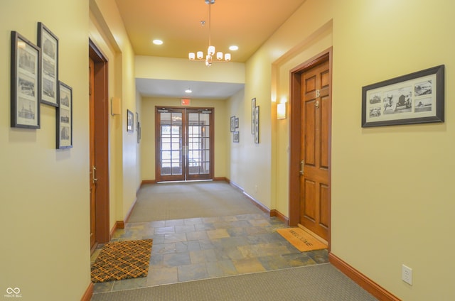 corridor featuring french doors, an inviting chandelier, and carpet floors