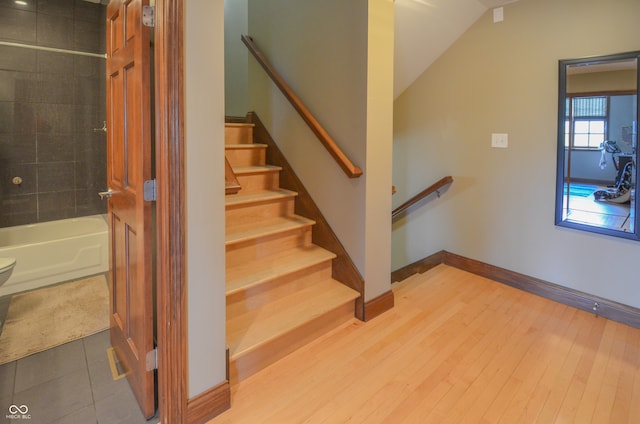 stairway featuring lofted ceiling and wood-type flooring