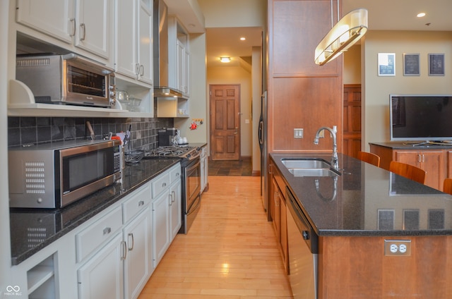 kitchen with light wood-type flooring, stainless steel appliances, white cabinetry, and sink