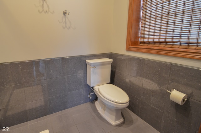 bathroom with tile walls, toilet, and tile patterned flooring