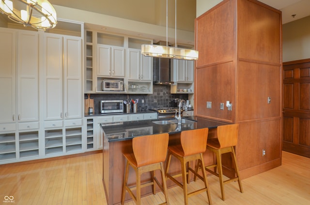 kitchen featuring a breakfast bar area, light hardwood / wood-style flooring, backsplash, sink, and white cabinets