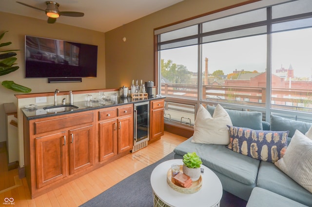 living room with wet bar, beverage cooler, light hardwood / wood-style flooring, and ceiling fan