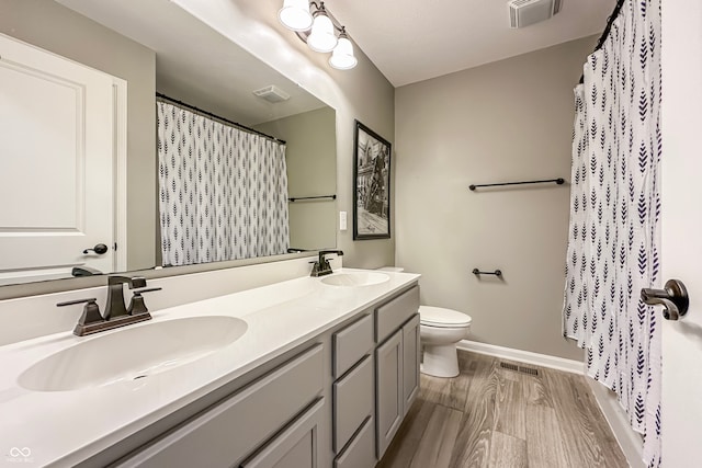 bathroom with wood-type flooring, vanity, walk in shower, and toilet