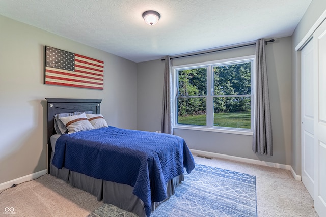 carpeted bedroom with a closet and a textured ceiling