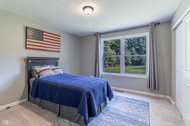 bedroom with carpet flooring, visible vents, a textured ceiling, and baseboards