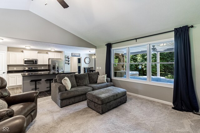 living room with vaulted ceiling, ceiling fan, and light colored carpet