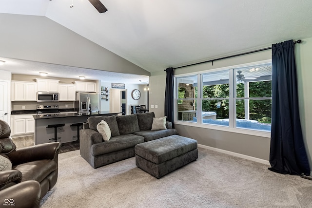 living room featuring ceiling fan, carpet floors, high vaulted ceiling, and baseboards