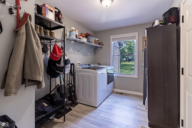 laundry room with light wood-type flooring, washer and dryer, laundry area, and baseboards