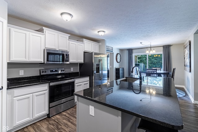 kitchen with a kitchen island with sink, appliances with stainless steel finishes, sink, and white cabinetry