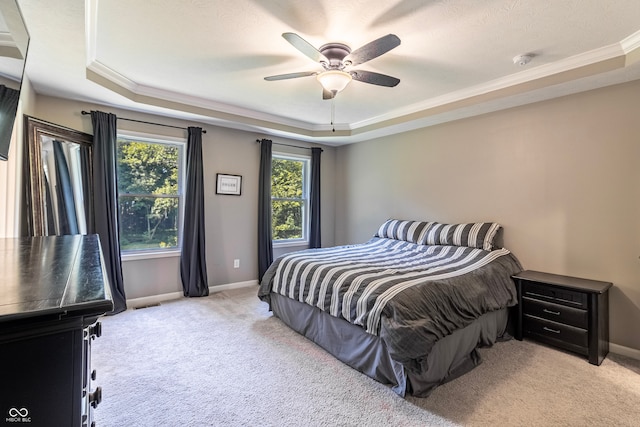 carpeted bedroom featuring crown molding, a tray ceiling, and ceiling fan